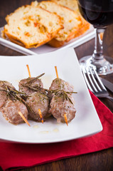 Meat skewers on white dish.