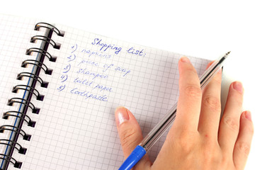 woman's hand holding a notebook with a shopping list close-up