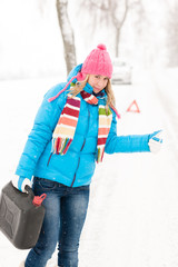 Woman hitchhiking on road snow gas can