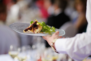 Fototapeta na wymiar Kelnerka niosąc talerz z dania mięsnego