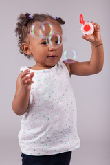 Little African American girl playing with soap bubbles