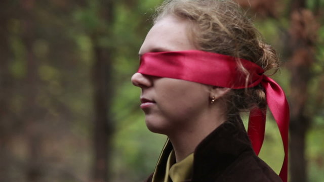 Man leads his girlfriend with blindfold in forest