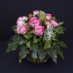 Rosen in runder Glasvase auf Schwarz