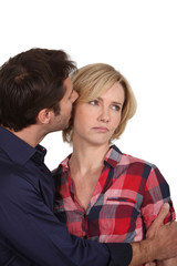 Man whispering in an unhappy woman's ear