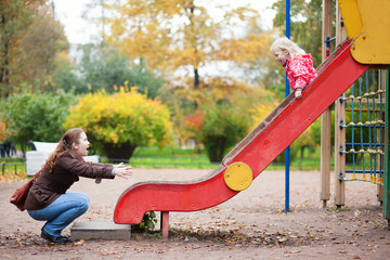 Mother and her little daughter are having fun together at the pl