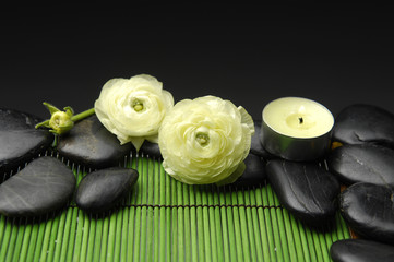 ranunculus flower with stones and candle on mat