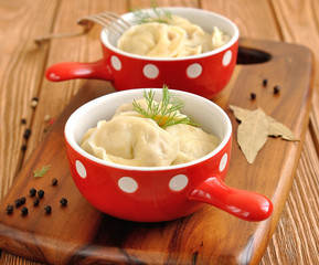 pelmeni in a red bowl on a brown table