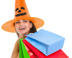 Happy woman in Halloween hat with shopping bags looking on copy
