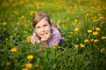 Fototapeta premium Little girl lying in grass hold flower in hand