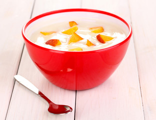Yogurt with peach in bowl on wooden background