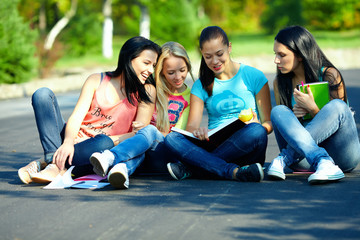 four beautiful girls friends read books, sitting on the ground