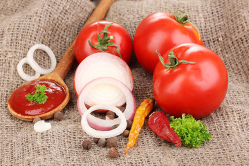 Ketchup and ripe tomatoes on sacking close-up