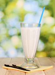 Vanilla milk shake on wooden table on bright background