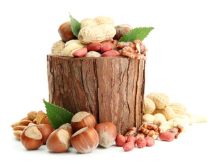 assortment of tasty nuts with leaves in wooden vase, isolated