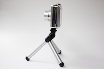 miniature camera and tripod against white background