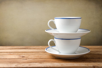 Two coffee cups on wooden tabletop against grunge background