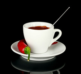 white cup with hot chocolate and chili pepper isolated on black