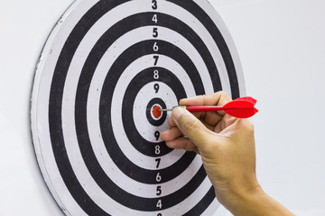 Hand and red dart on dartboard