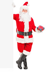 Happy Santa claus standing next to a billboard and holding a gif