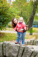 Fototapeta na wymiar Outdoor portrait of beautiful mother and daughter on a little br