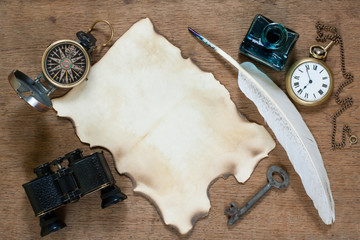 Compass, pocket watch, quill, inkwell, paper, binoculars on wood