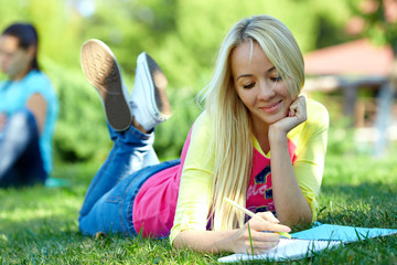 beautiful female student learns outside on green lawn