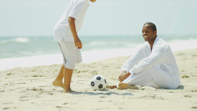 Diverse happy parent spending time with child playing soccer