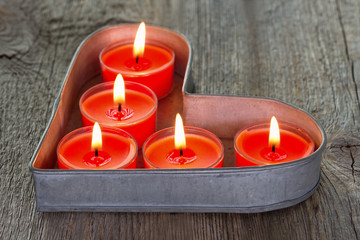 Obraz na płótnie Canvas Red candles on a heart shaped tin tray