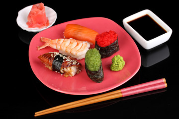 delicious sushi served on red plate isolated on black
