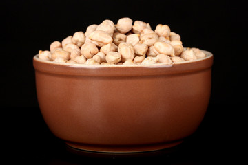 White chickpeas in brown bowl isolated on black