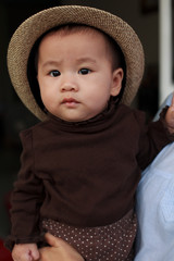 face of asian baby wearing straw hat