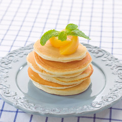 Golden pancakes topping with peach and mint
