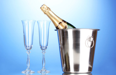 Champagne bottle in bucket with ice and glasses