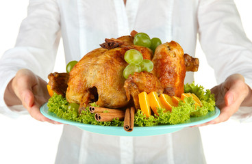 Chef holding a plate of baked chicken with fruit and spices