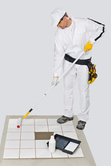 Fototapeta premium worker paint with primer old tiles floor with roller