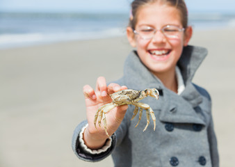 Adorable happy girl holding crab