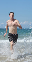 Athletic man jogging at the beach