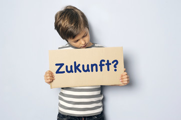 Kind mit Schild fragt nach seiner Zukunft