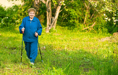 Active woman (85 years old) nordic walking outdoors.