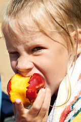 Little girl eating a peach