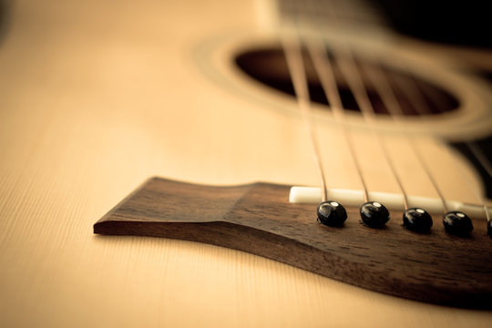 Macro shot down the fretboard of acoustic guitar with shallow de