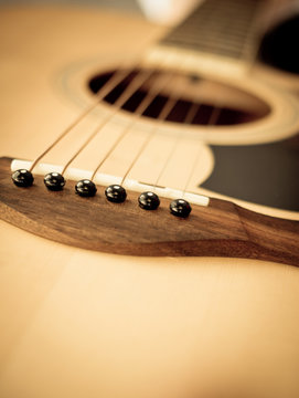 Macro shot down the fretboard of acoustic guitar with shallow de