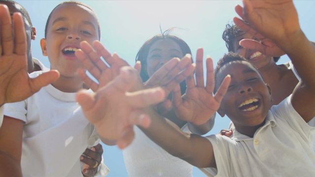 Close up of ethnic family waving on video call together on beach