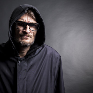 portrait of a man with a beard wearing glasses and hood