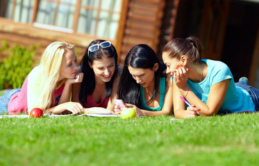 four beautiful girls chatting in social network on green lawn