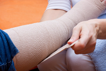 Pflegerin bandagiert den Fuss einer Patientin