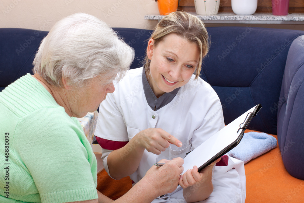 Wall mural seniorin und pflegerin sitzen beieinander, daten werden notiert