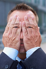 Mann mit Händen und Augen vor dem Gesicht