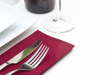 Place setting with white plates and red wine and red napkin