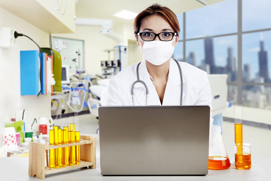 Doctor with laptop and flasks looking at camera